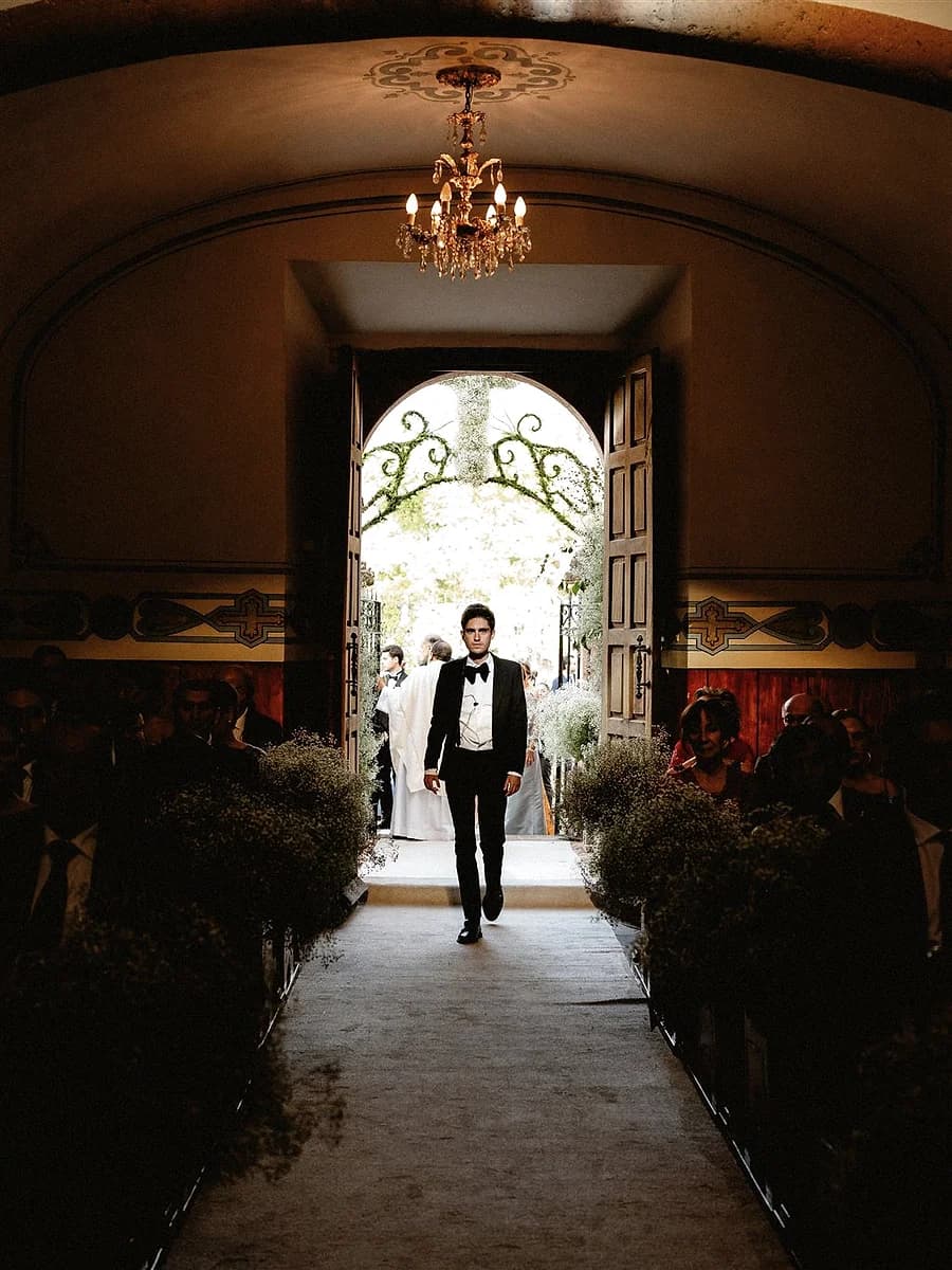 Entrada arquitectónica con pareja al fondo en una boda editorial