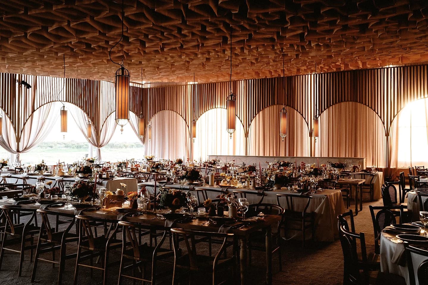 Salón de recepción con mesas largas y dirección floral cálida