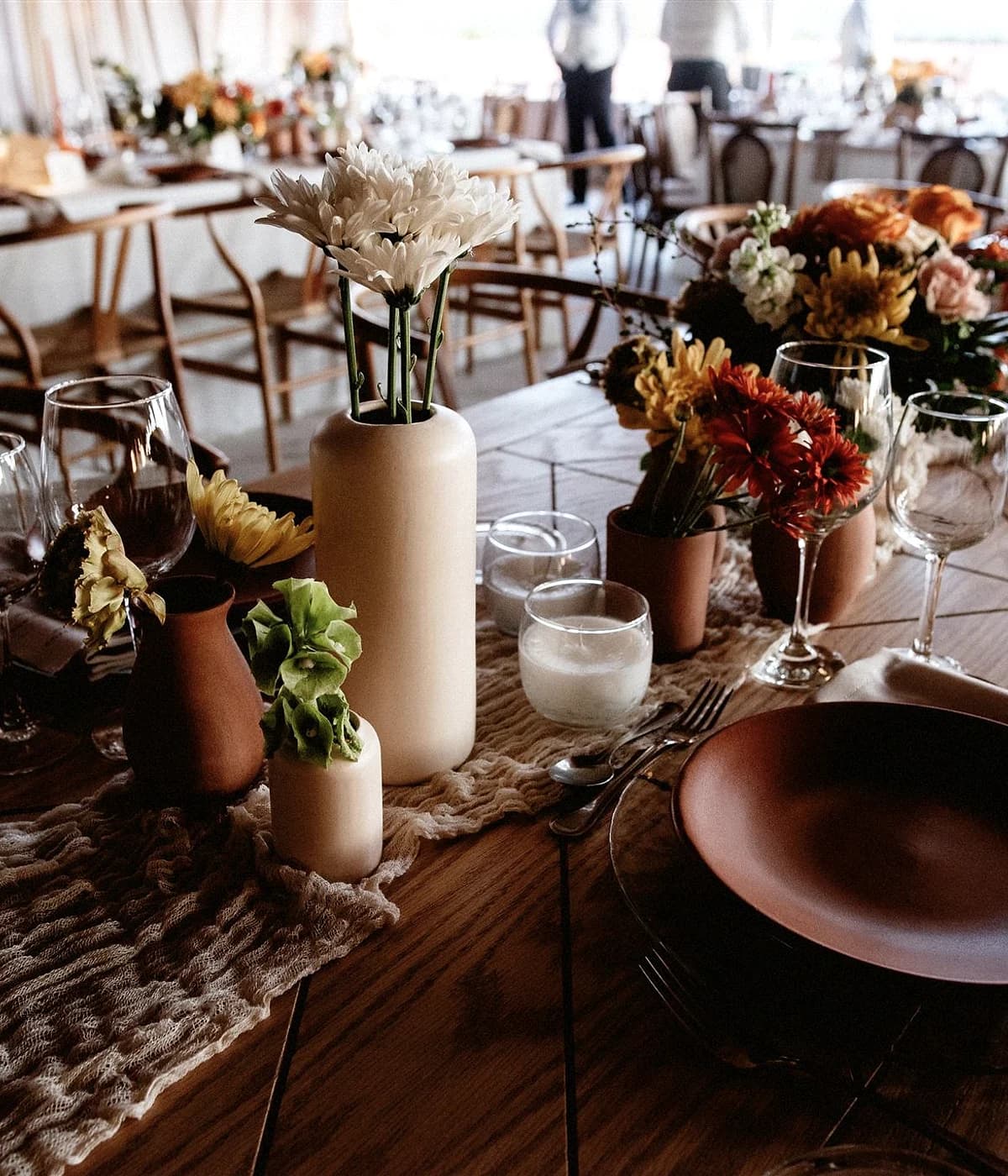 Mesa editorial con platos terracota, flores y cristalería